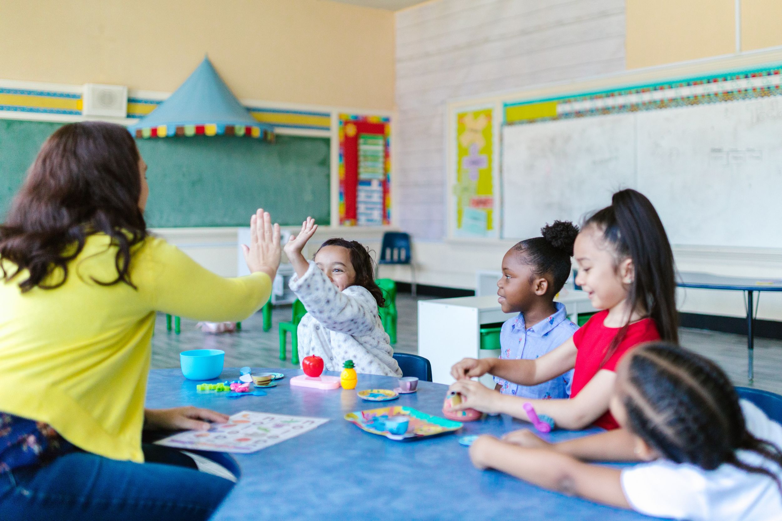 Teacher high fives young student.