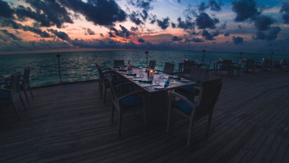 Blue cushioned wooden restaurant chairs on a boardwalk.