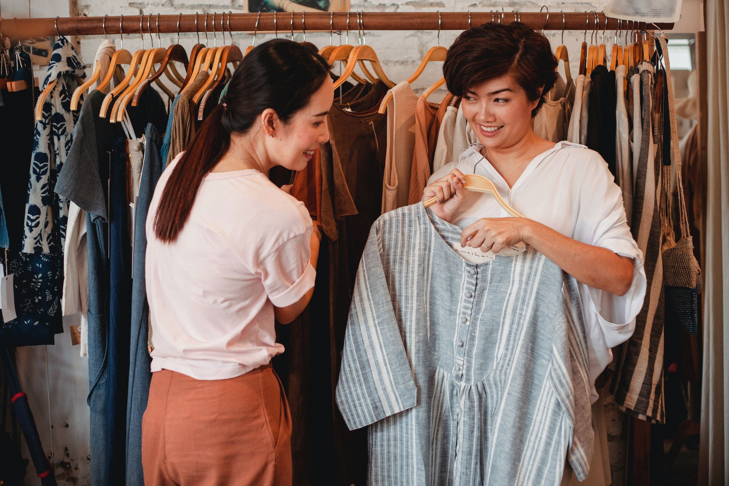 Two women look at the tag of a shirt in a clothing store.