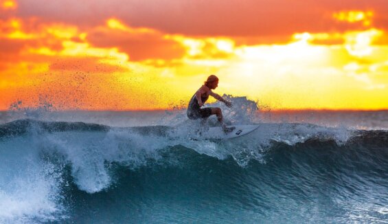 Man surfs small wave at sunset.