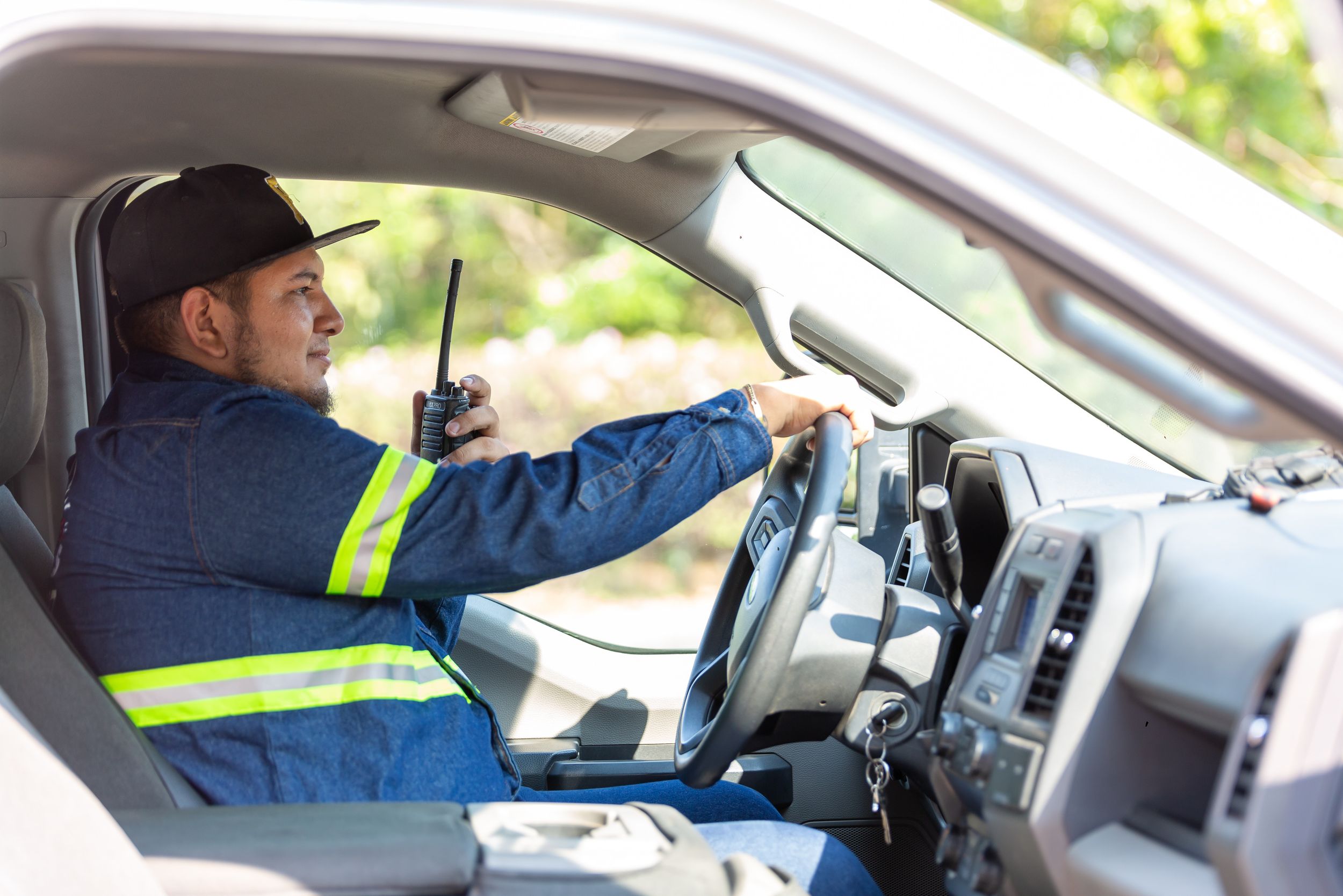 Emergency personnel driving a vehicle and speaking on a walkee talkee.